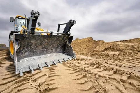 A universal excavator loader is moving dirt on a construction site. The mac.. Stock Photos