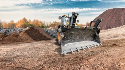 A universal excavator loader is moving dirt at a construction site. The mac.. Stock Photos