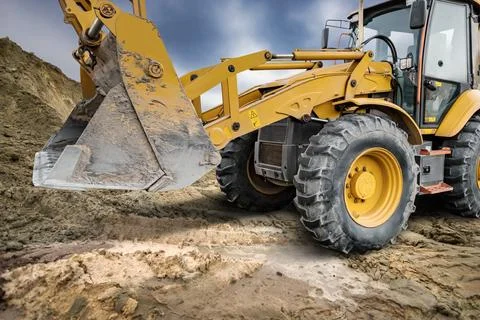A universal excavator loader is moving dirt at a construction site. The loa.. Stock Photos