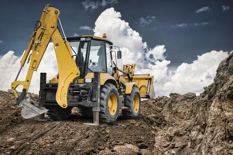 A universal excavator loader operates on a construction site, moving dirt. .. Stock Photos