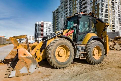 A universal excavator or loader is working on a construction site. Close-up.  Photos