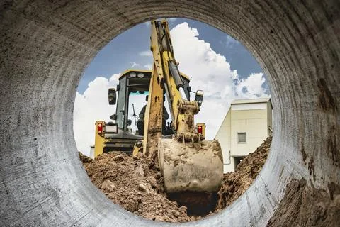A universal excavator is working on a construction site against a cloudy sk.. Photos
