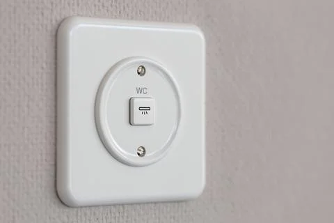 Universal wall light switch for water closet or toilet on wall panel. Stock Photos
