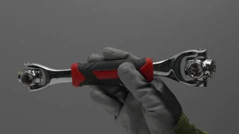 A universal wrench rotates in a hand on a gray background. Video stock 266985177