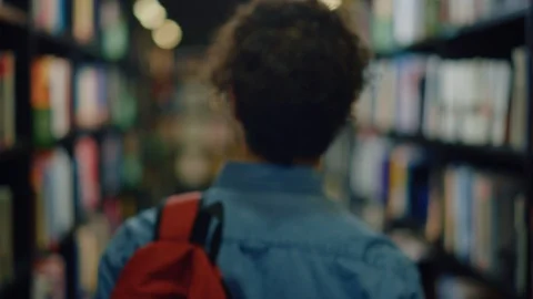 University Library: Student Walks Between Bookshelves Searching for Right Book Stock Footage 126916502