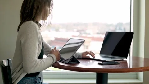 University student expertly balancing work on a tablet and a laptop in a ligh Video stock 274656812