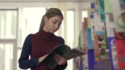 University student looking through the book in library Stock-Footage 74458460