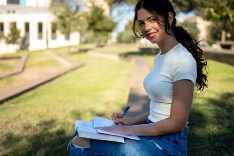University student taking notes while sitting outdoors on campus Stock Photos