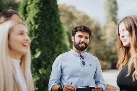 University students collaborate outside while studying subjects, solving Stock Photos