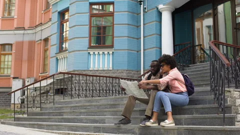 University students looking at map, sitting building on stairs, sightseeing trip Vídeos de archivo 91799453
