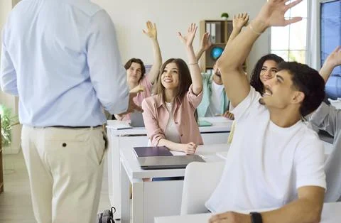 University students raise hands in class, asking question to teacher during Stock Photos