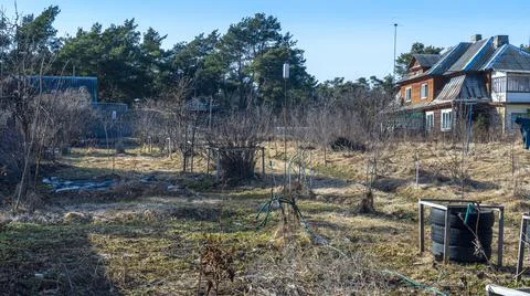 An unkempt plot of land in the village in early spring with withered grass, a Stock Photos