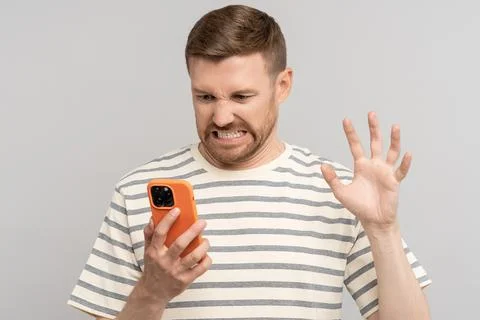 Unkind guy angry looks screen smartphone, aggressive video call, twisting face Stock Photos