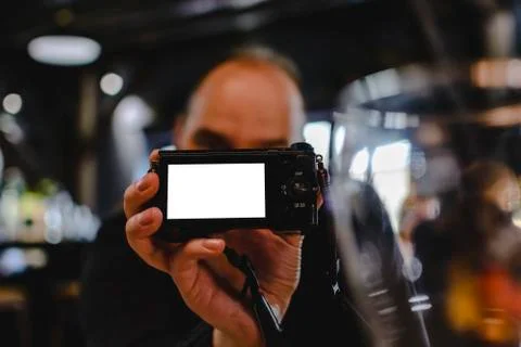 Unknown blurry man holding a camera with blank space for text on screen. Stock Photos