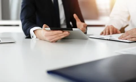 Unknown business people using tablet computer in sunny office. Businessman is Stock Photos