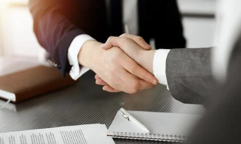 Unknown businessman shaking hands with his colleague or partner above the desk Stock Photos