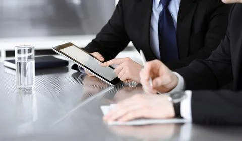 Unknown businessmen using tablet computer and work together at the glass desk in Stock Photos