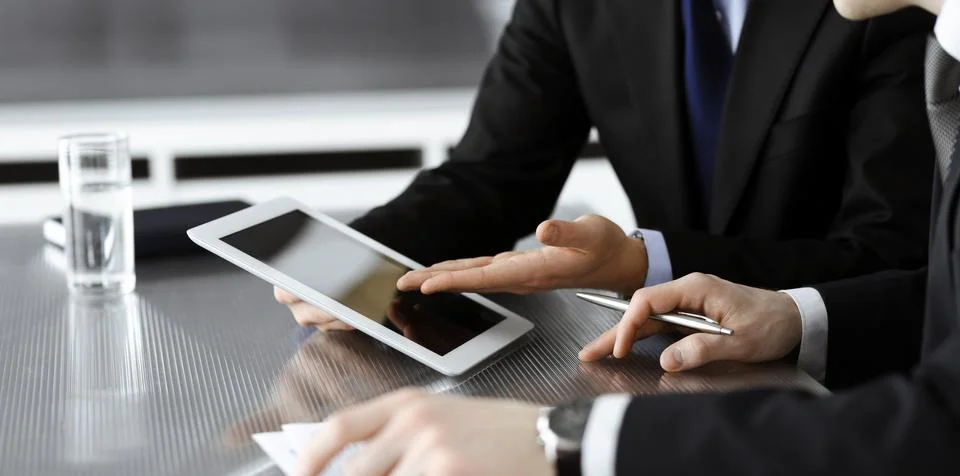 Unknown businessmen using tablet computer and work together at the glass desk in Stock Photos