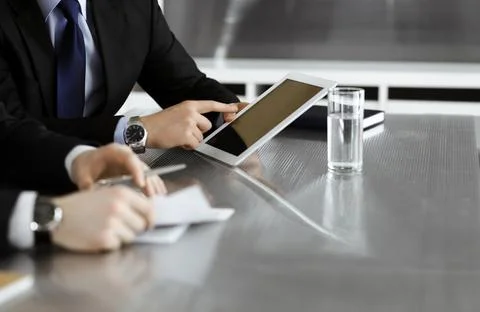 Unknown businessmen using tablet computer and work together at the glass desk in Stock Photos
