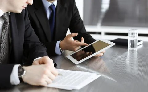 Unknown businessmen using tablet computer and work together at the glass desk in Stock Photos