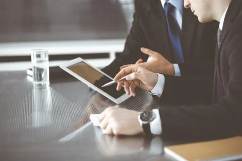 Unknown businessmen using tablet computer and work together at the glass desk in Stock Photos
