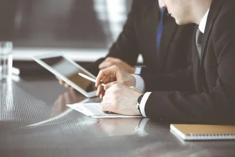 Unknown businessmen using tablet computer and work together at the glass desk in Stock Photos