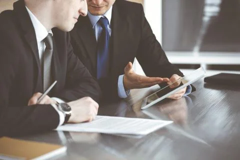 Unknown businessmen using tablet computer and work together at the glass desk in Stock Photos