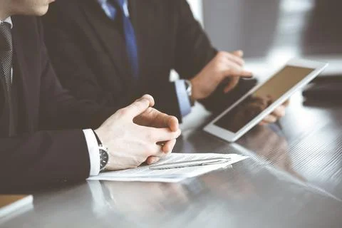 Unknown businessmen using tablet computer and work together at the glass desk in Stock Photos