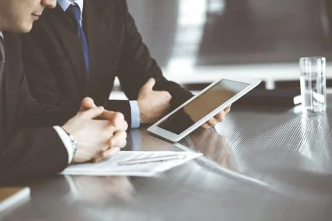 Unknown businessmen using tablet computer and work together at the glass desk in Stock Photos
