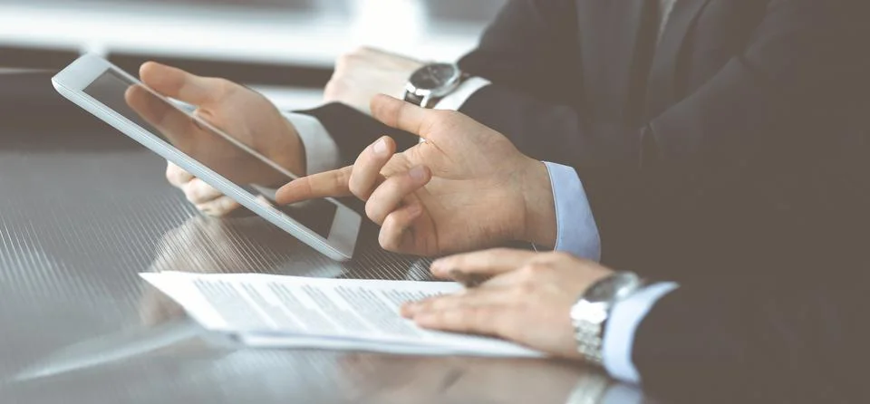 Unknown businessmen using tablet computer and work together at the glass desk in Foto stock
