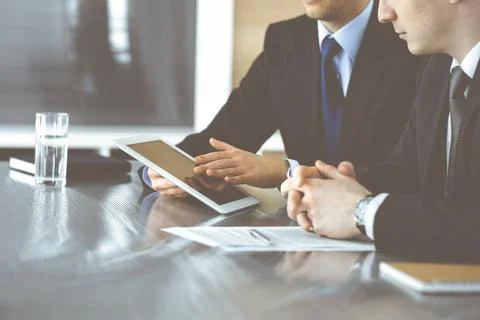 Unknown businessmen using tablet computer and work together at the glass desk in Stock Photos