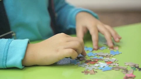 Unknown child collecting puzzles at the table Stock Footage 80929414