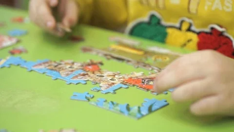Unknown child collecting puzzles at the table Stock Footage 80929576