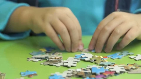 Unknown child collecting puzzles at the table Stock-Footage 80930532