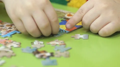 Unknown child collecting puzzles at the table Stock Footage 81838490