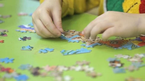 Unknown child collecting puzzles at the table Stock Footage 81838756