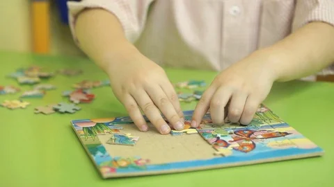 Unknown child collecting puzzles at the table Stock Footage 81840172