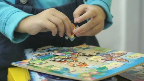 Unknown child collecting puzzles at the table Stock Footage 82443373