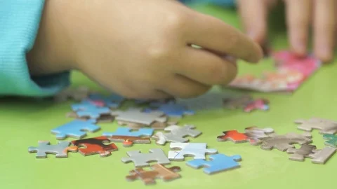 Unknown child collecting puzzles at the table Stock Footage 83995695