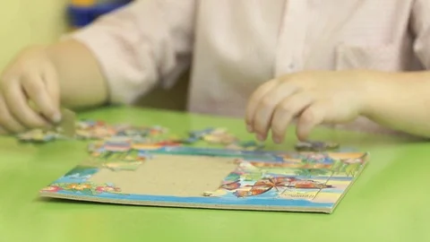 Unknown child collecting puzzles at the table Stock Footage 83996411