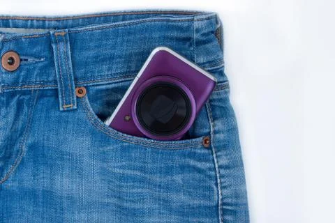 Unknown compact camera is lying in the side pocket of blue jeans. Stock Photos