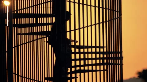 Unknown dad and his son climb up spiral staircase together on orange sky Stock Footage 228116785