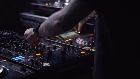 Unknown DJ is playing a fat beat. Hands are turning knobs on a mixer. 動画素材 118390072