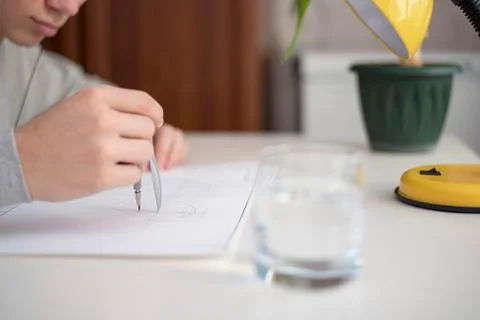 Unknown draws with a compass, on white paper, sitting at white table Stock Photos