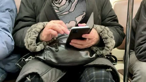 An unknown elderly woman, casually engaged with her smartphone, navigated the Vidéo 316463798