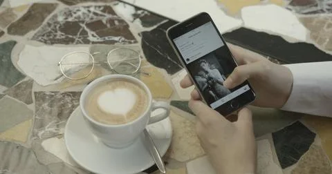 Unknown girl is using the instagram app and scrolling photos of young brunette Stock Photos