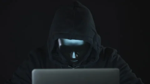 Unknown hacker or robot wearing black clothes and mask uses the computer Stock Footage 137610438