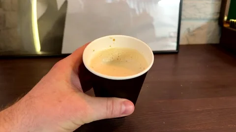 Unknown hand holding brown disposable paper cup with coffee from first face Stock Footage 302097499