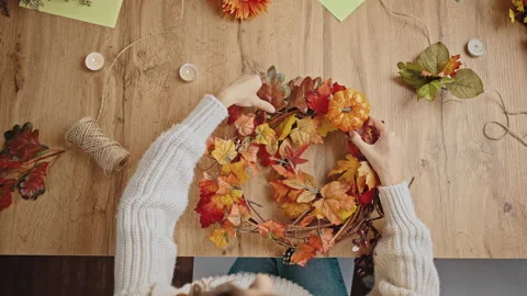 Unknown lady making wreath of orange autumn leaves, pumpkin and pine cones Stock Footage 164677565