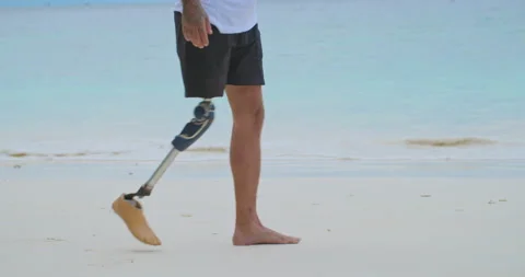 Unknown man with artificial bionic legs walking along the beach in summer. Video stock 210725948